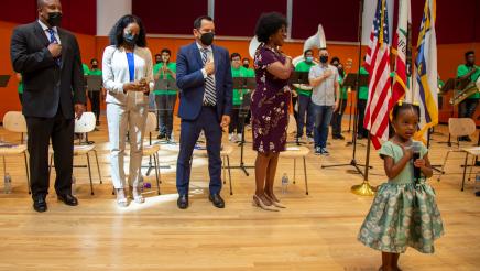 Small girl holding microphone, leading the Pledge of Allegiance