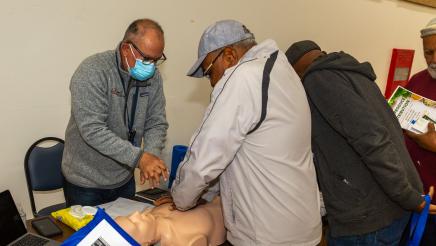 Constituent being taught CPR at educational table