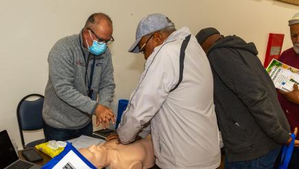 Constituent being taught CPR at educational table