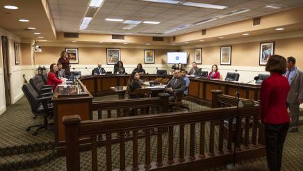 Witness stands toward the back of the hearing room as the comittee listens on