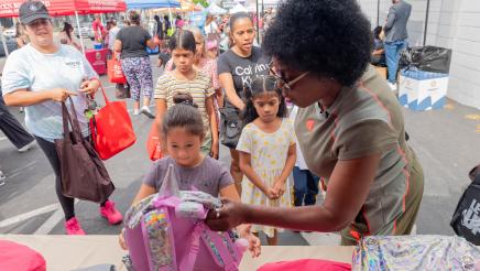 Asm. McKinnor helping young student select backpack