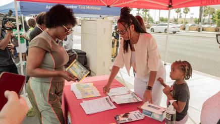 Asm. McKinnor viewing informational materials with booth staffer