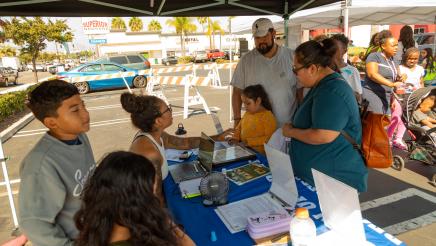 Informational booth staffers sharing information with family