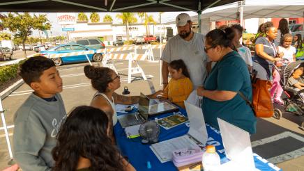Informational booth staffers sharing information with family