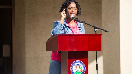 Guest speaker at podium, speaking and pointing with one hand