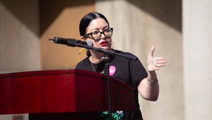 Guest speaker at podium, speaking and gesturing to one side