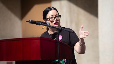 Guest speaker at podium, speaking and gesturing to one side