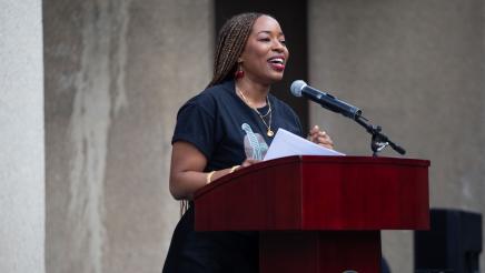Guest speaker at podium, holding paper and speaking