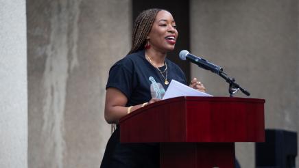 Guest speaker at podium, holding paper and speaking