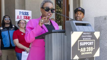 Asm. McKinnor at podium in front of Capitol doors, speaking