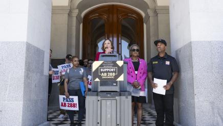 Guest speaker at podium in front of Capitol doors, speaking